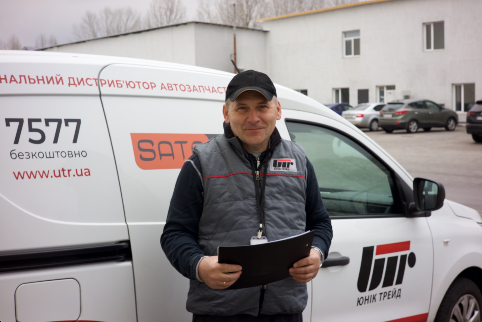 Працівник доставки поруч із автомобілем Юнік Трейд